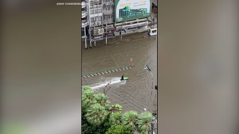 Un hombre en moto de agua recorre las calles inundadas de Bangkok